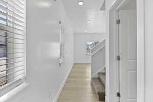 Light wood-finish flooring extending through a brightly lit hallway