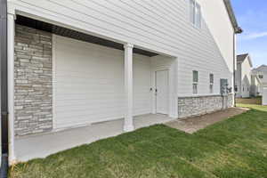 Covered patio area featuring a concrete slab and a white paneled entry door