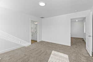 Spacious room with plush carpet flooring, recessed ceiling light, and white baseboards