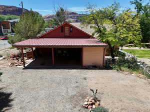 Red-painted exterior featuring a metal roof and a covered carport with exposed wood beams