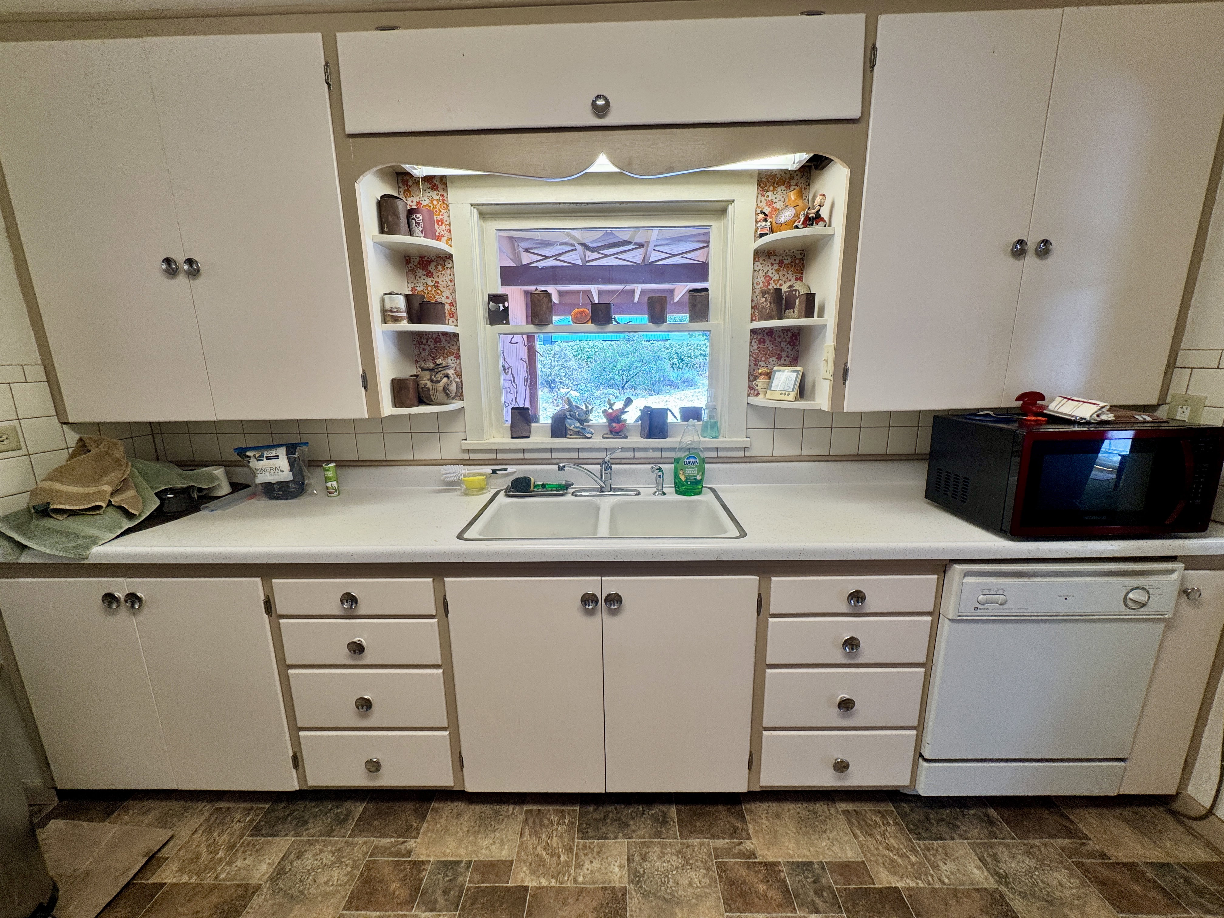 Kitchen area featuring upper and lower cabinetry, a double basin sink, and a built-in dishwasher