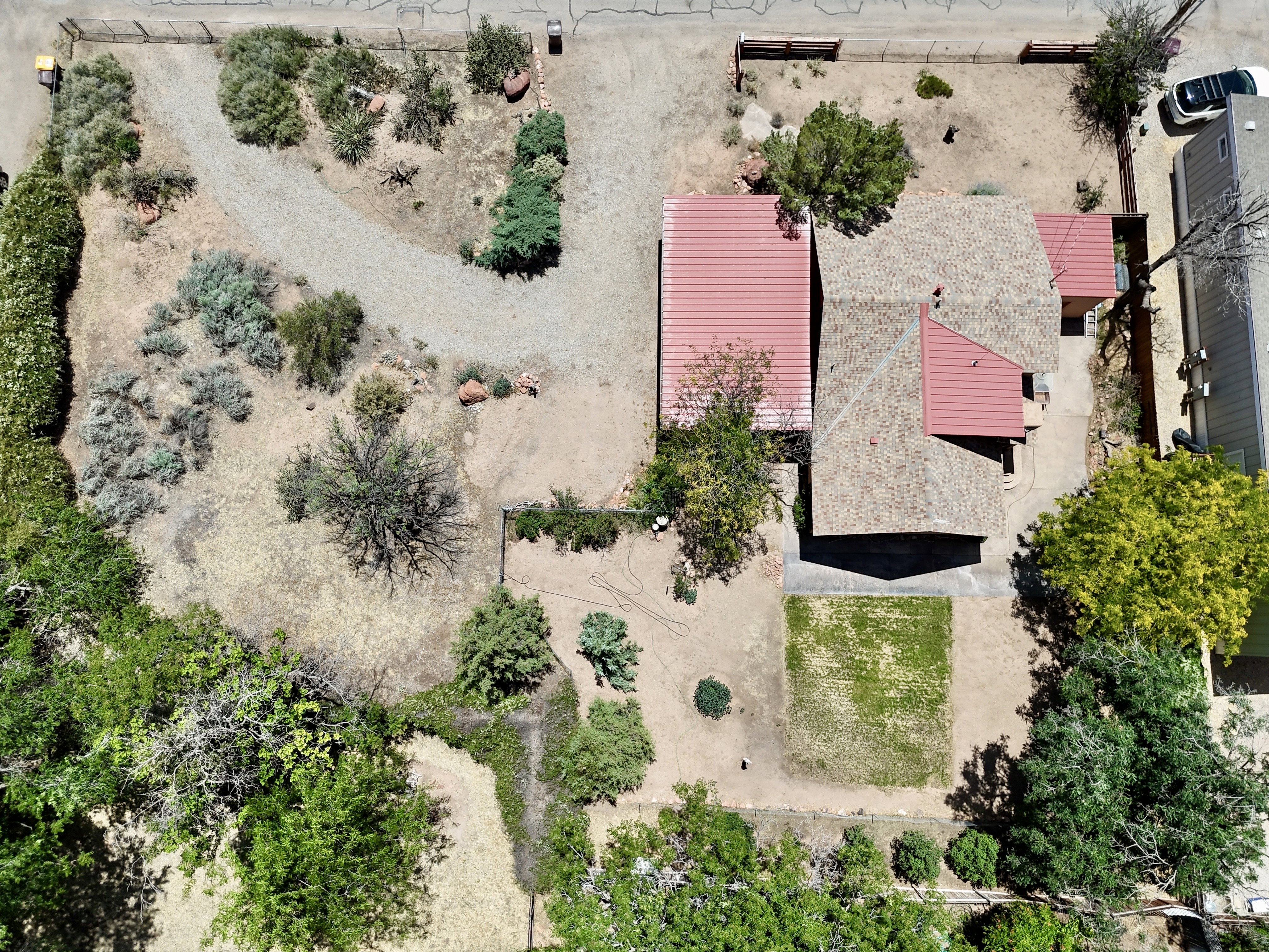 Property featuring a red metal roof section, a shingled roof section, and a gravel driveway
