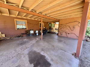 Covered outdoor patio with exposed beam ceiling and concrete flooring