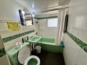 Bathroom featuring white subway tile walls with a decorative green mosaic accent, a green pedestal sink, a green toilet, and a green bathtub with a shower curtain