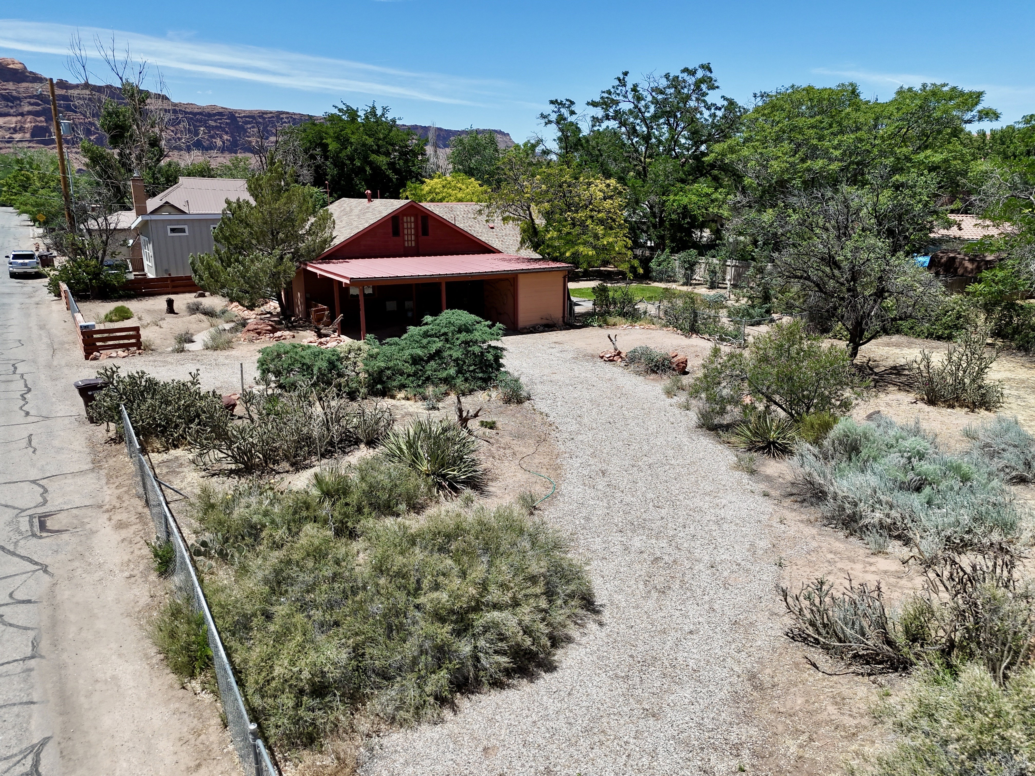 Red-roofed residence with an attached carport, gravel driveway, and surrounding desert landscaping