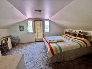Attic room featuring sloped ceilings, light-colored wall surfaces, and a built-in headboard with integrated shelving