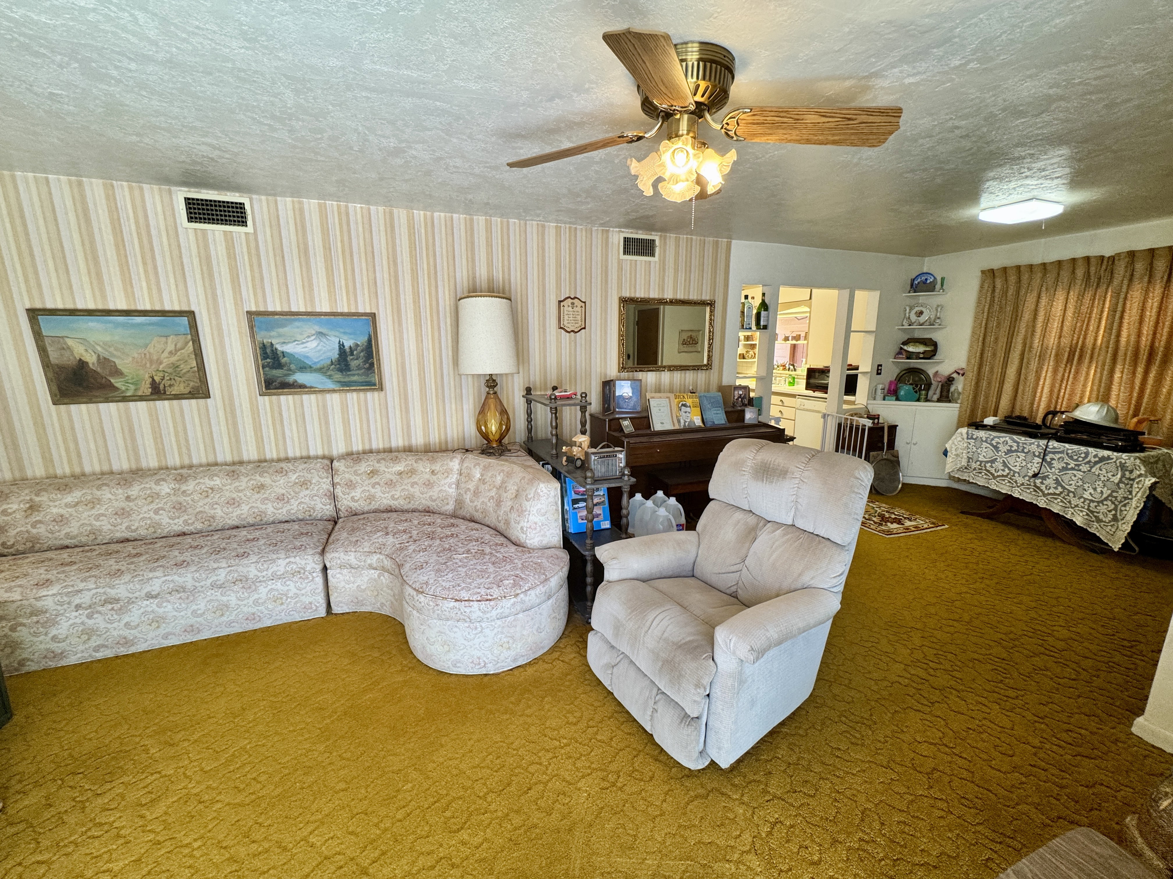 Living space featuring textured gold carpeting and striped wallpaper