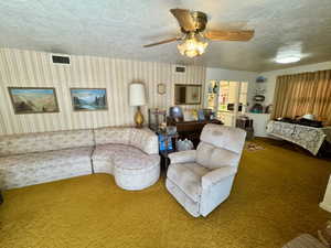 Living space featuring textured gold carpeting and striped wallpaper