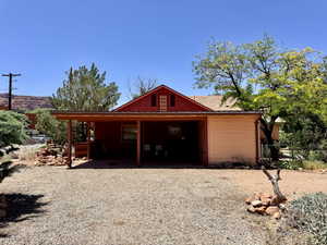 Red-sided residence featuring a covered carport, pitched roof, and a visible attic vent