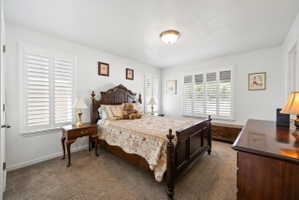 Bedroom featuring dark carpet and baseboards