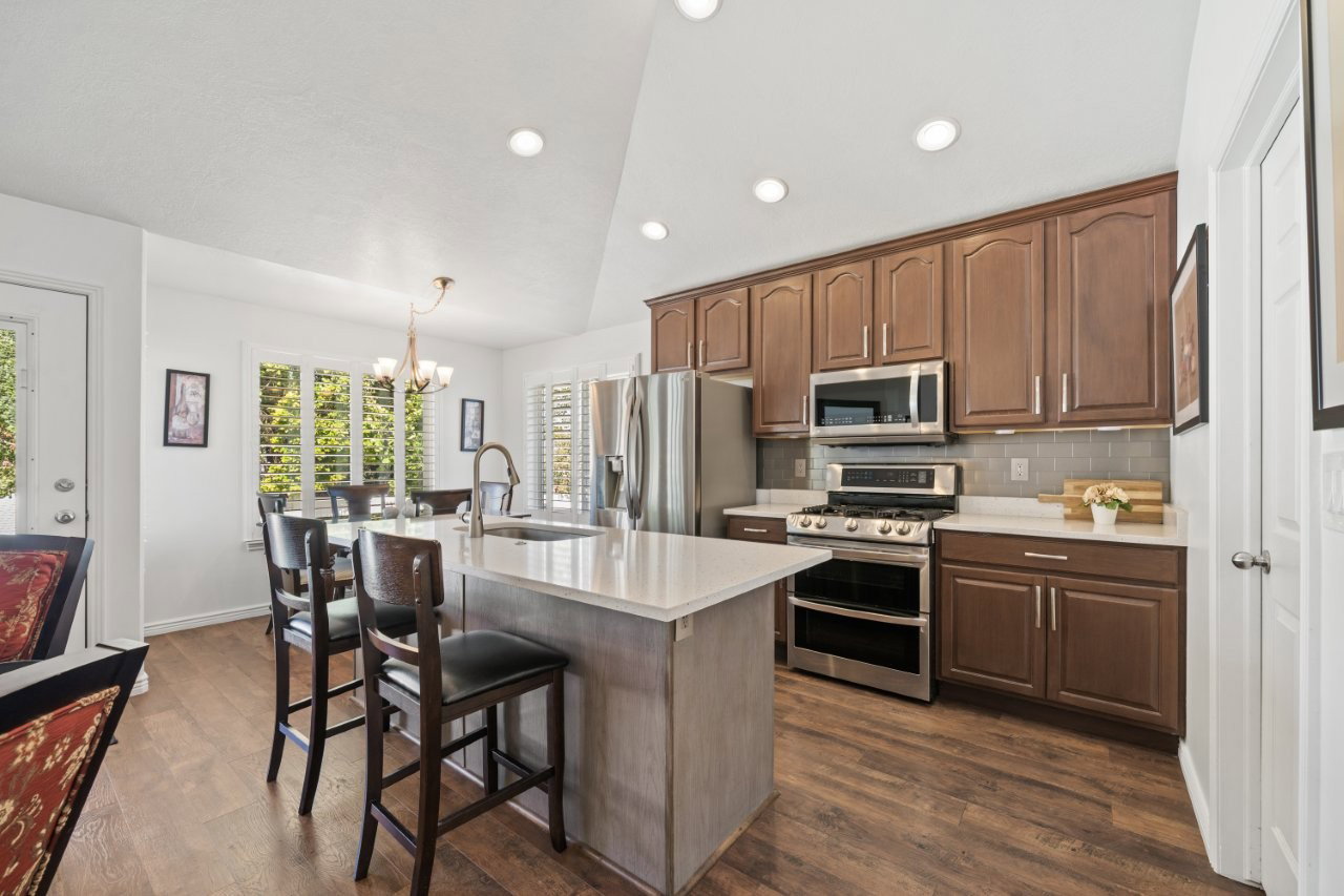Kitchen with stainless steel appliances, backsplash, lofted ceiling, dark wood-style floors, and a kitchen bar