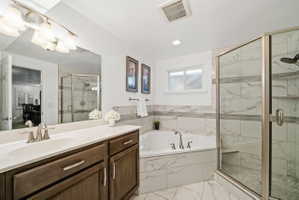 Full bath featuring a bath, a marble finish shower, vanity, light marble finish floors, and recessed lighting
