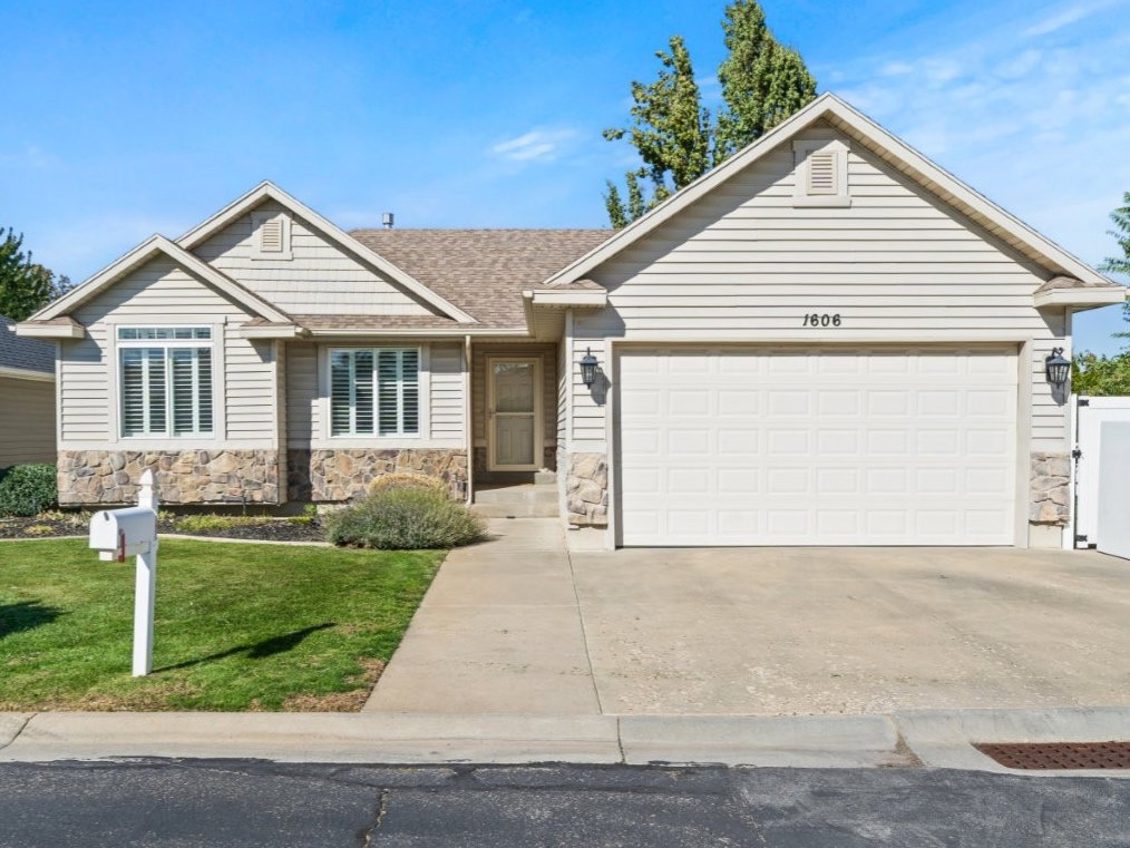 Single story home with concrete driveway, stone siding, an attached garage, and a shingled roof