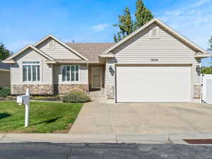 Single story home with concrete driveway, stone siding, an attached garage, and a shingled roof