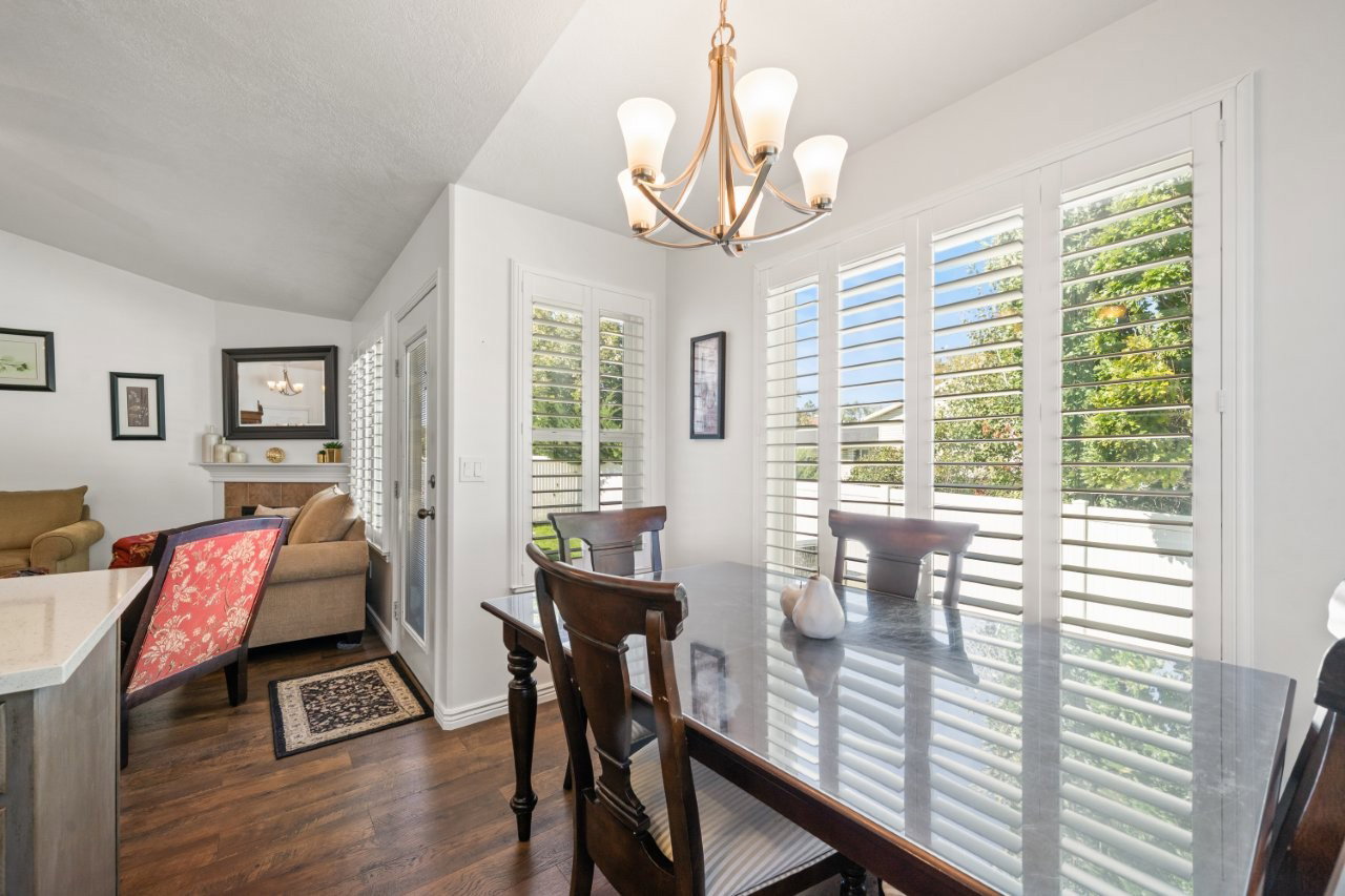 Dining area featuring dark wood-style flooring, vaulted ceiling, and a chandelier