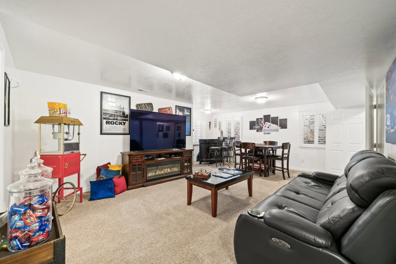 Carpeted living room with a glass covered fireplace and baseboards