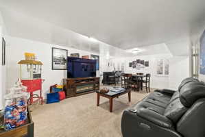 Carpeted living room with a glass covered fireplace and baseboards
