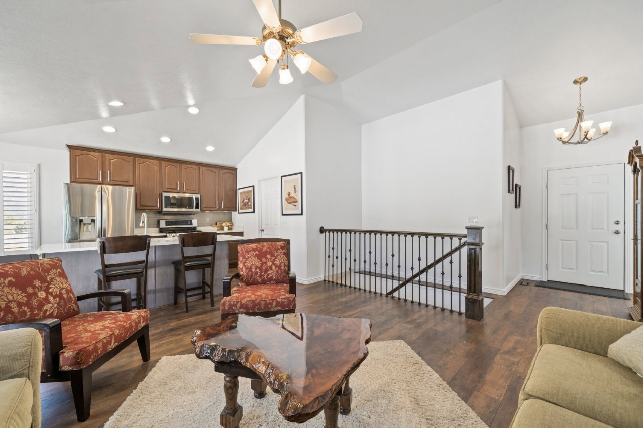 Living room with dark wood-style floors, recessed lighting, a chandelier, high vaulted ceiling, and ceiling fan