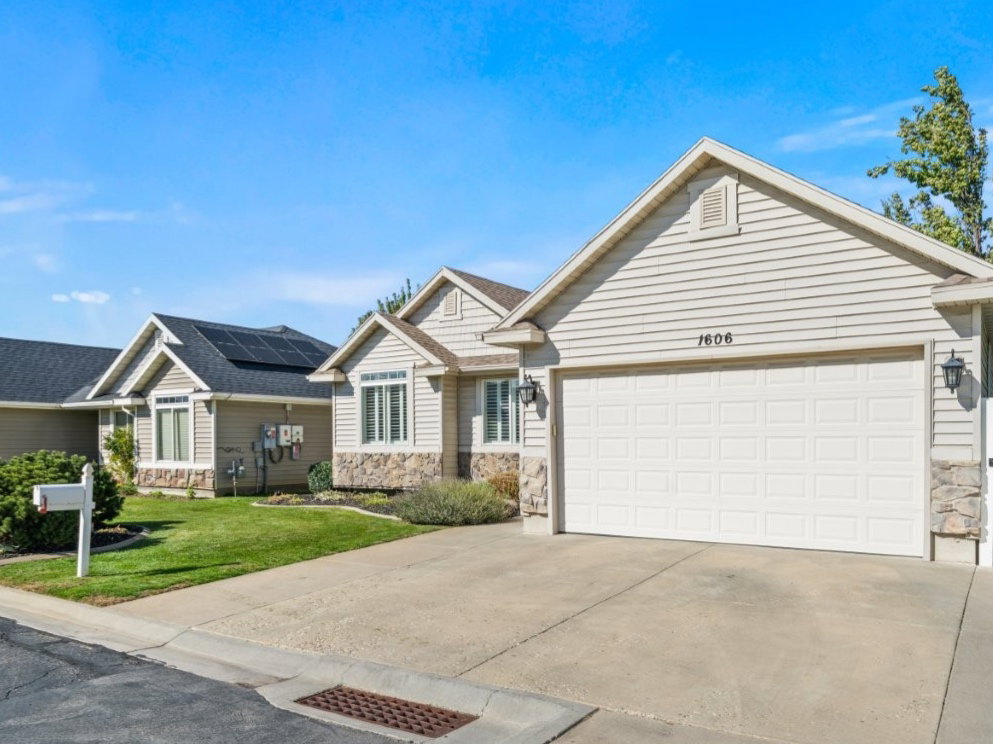 View of front of property featuring stone siding, driveway, a front yard, and a garage