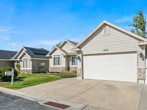 View of front of property featuring stone siding, driveway, a front yard, and a garage