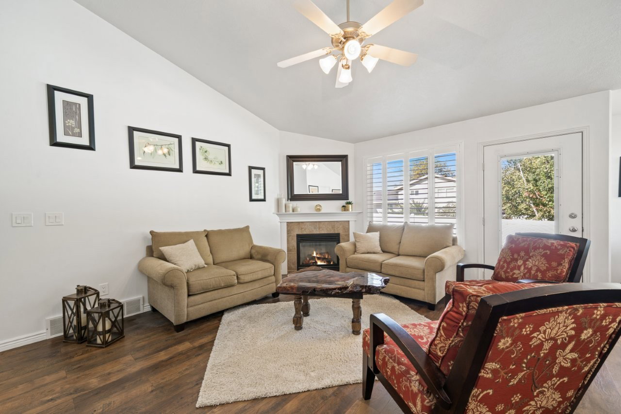 Living room featuring lofted ceiling, dark wood-type flooring, a tile fireplace, and ceiling fan