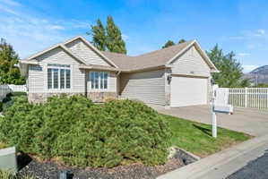 Ranch-style home featuring driveway, a garage, a shingled roof, and stone siding