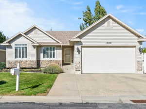 View of front of home with concrete driveway, stone siding, and a garage