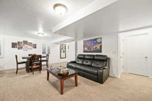 Living area with light colored carpet and a textured ceiling