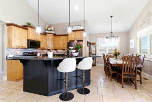 Spacious kitchen featuring natural wood cabinetry, dark countertops, a large island with beadboard paneling, and an integrated microwave