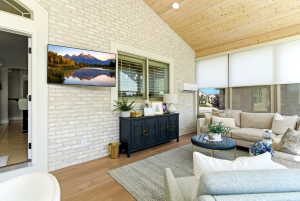 Vaulted tongue-and-groove wood ceiling in this inviting sunroom, featuring whitewashed brick walls and wood-finish flooring