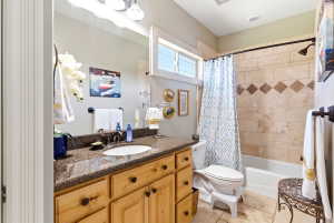 Bathroom featuring a light wood-finish vanity with a stone countertop and an undermount sink