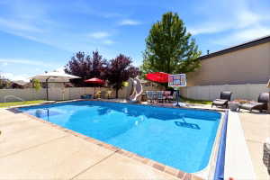 In-ground swimming pool featuring a perimeter of concrete decking with brick accents