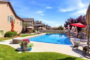Expansive backyard featuring a rectangular swimming pool, concrete pool deck, and mature landscaping