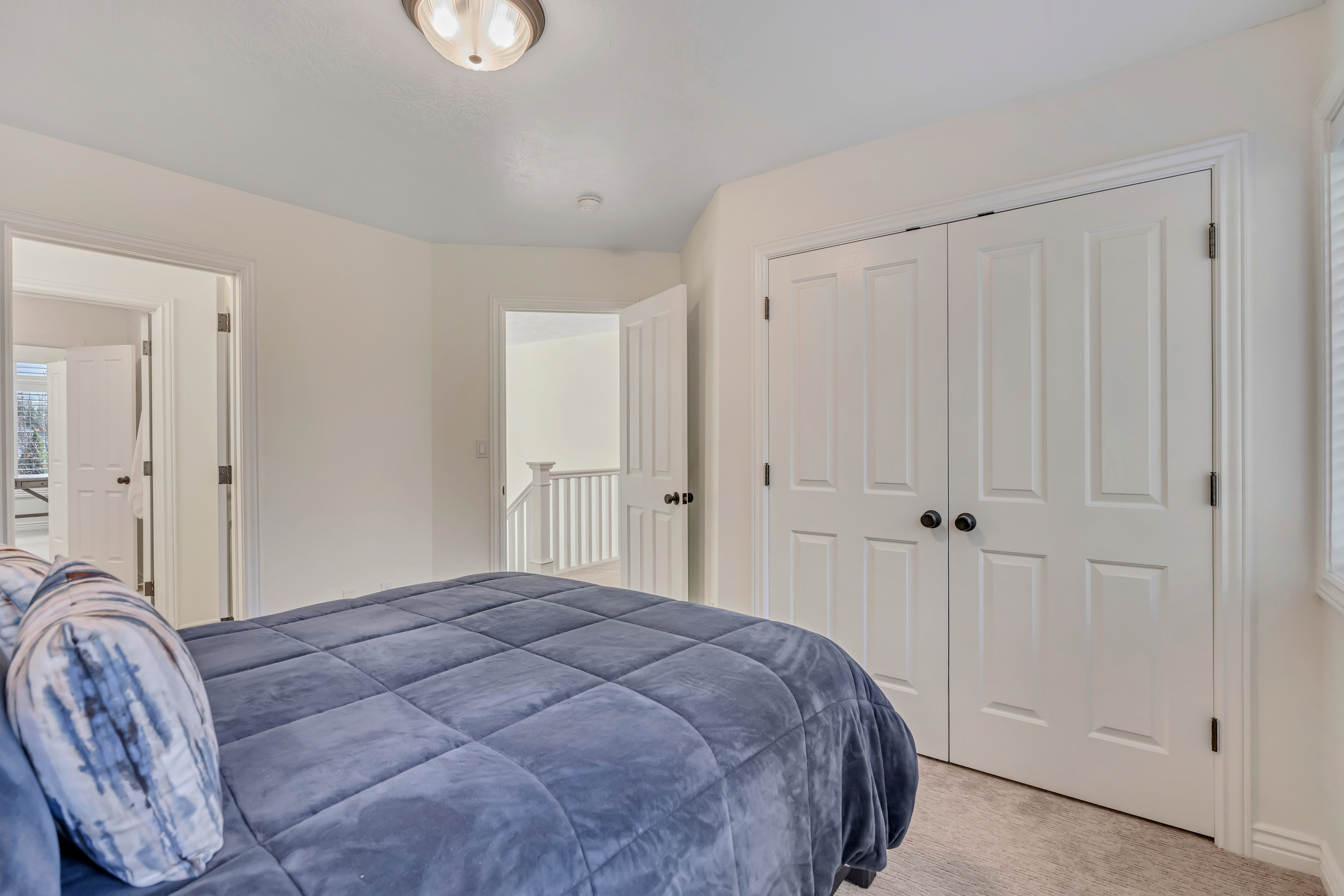 Bedroom with white paneled closet doors, neutral wall paint, and recessed lighting