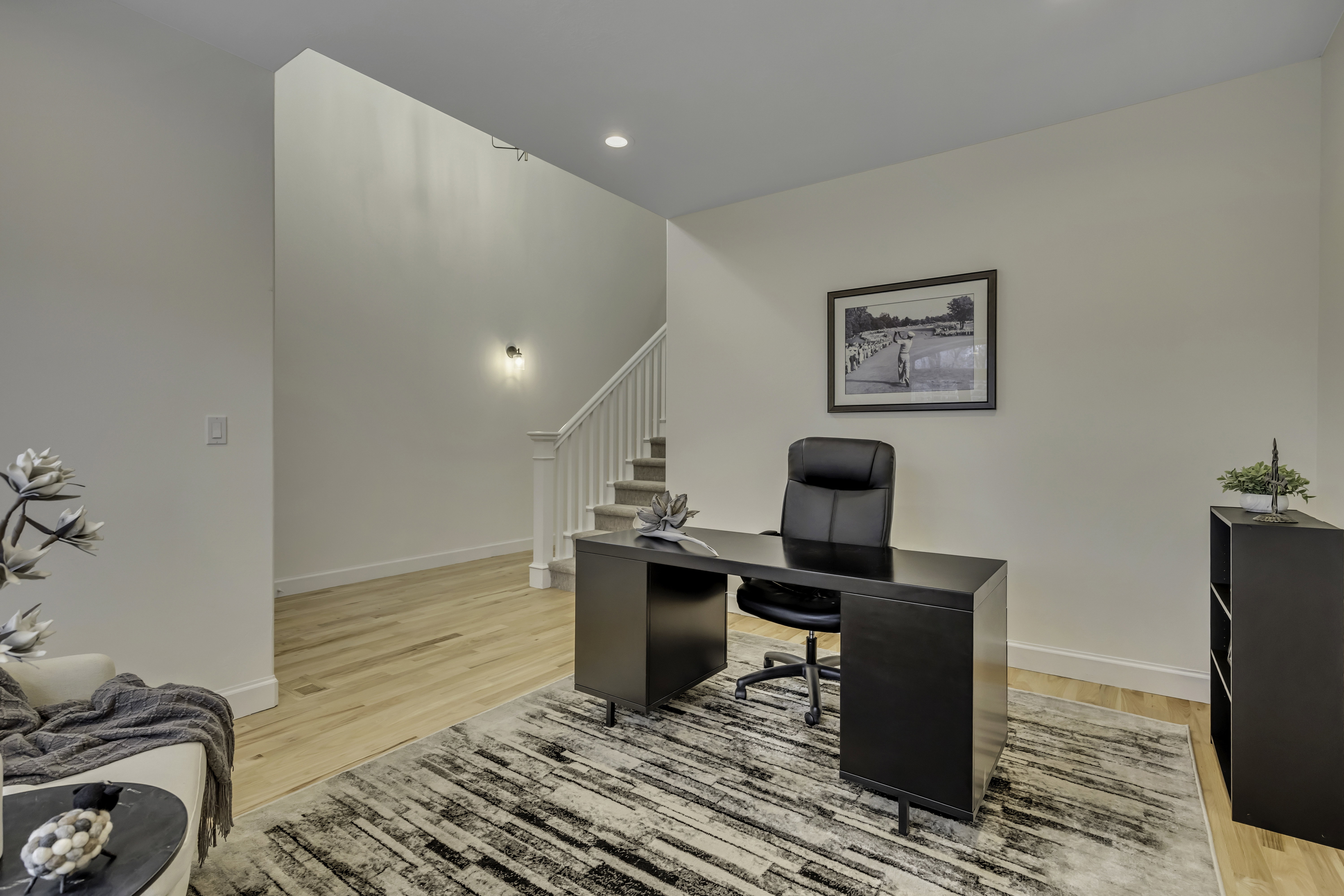 Hardwood flooring extends throughout this space, featuring crisp white walls and recessed ceiling lighting