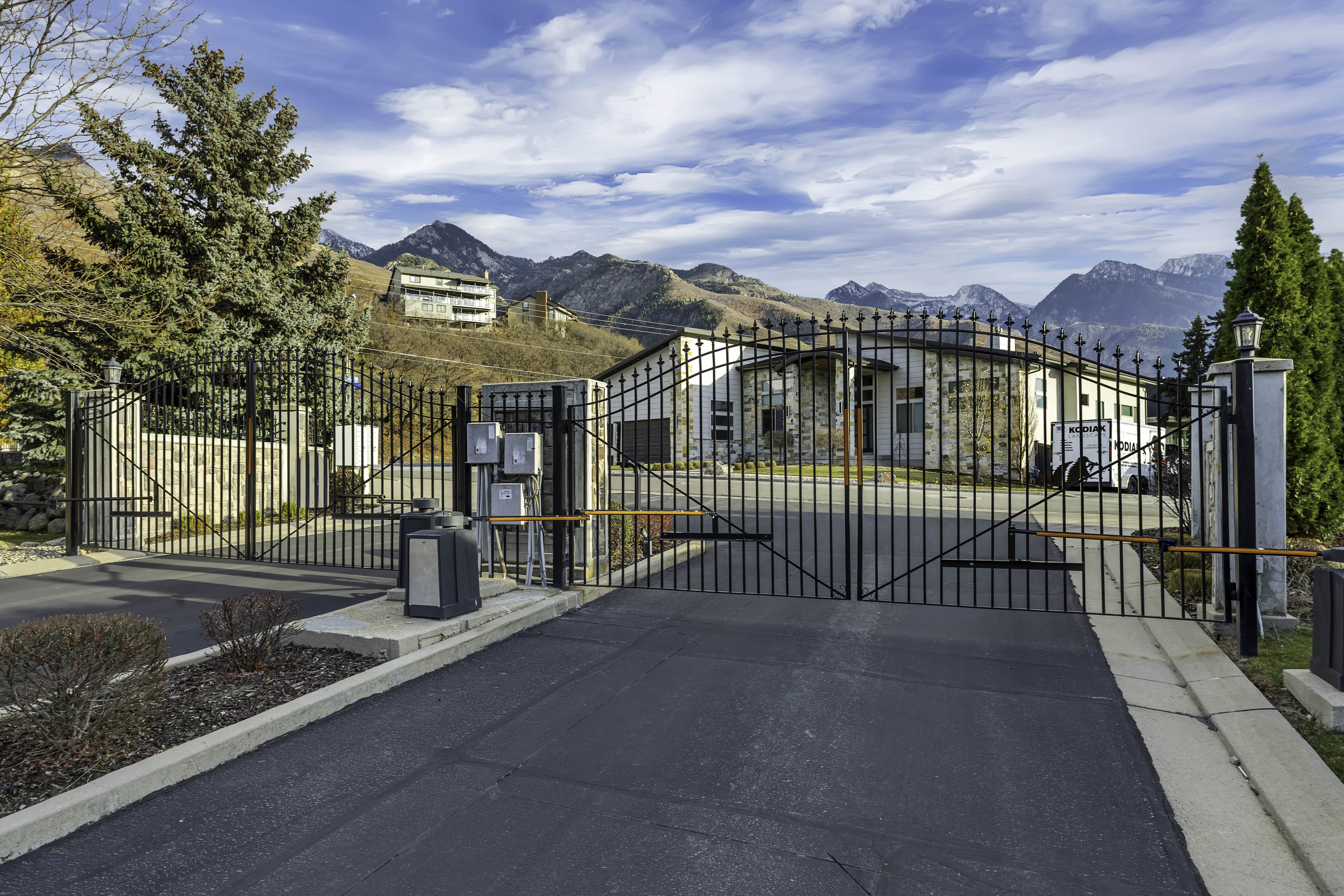 Gated property entrance featuring wrought iron fencing and a paved drive