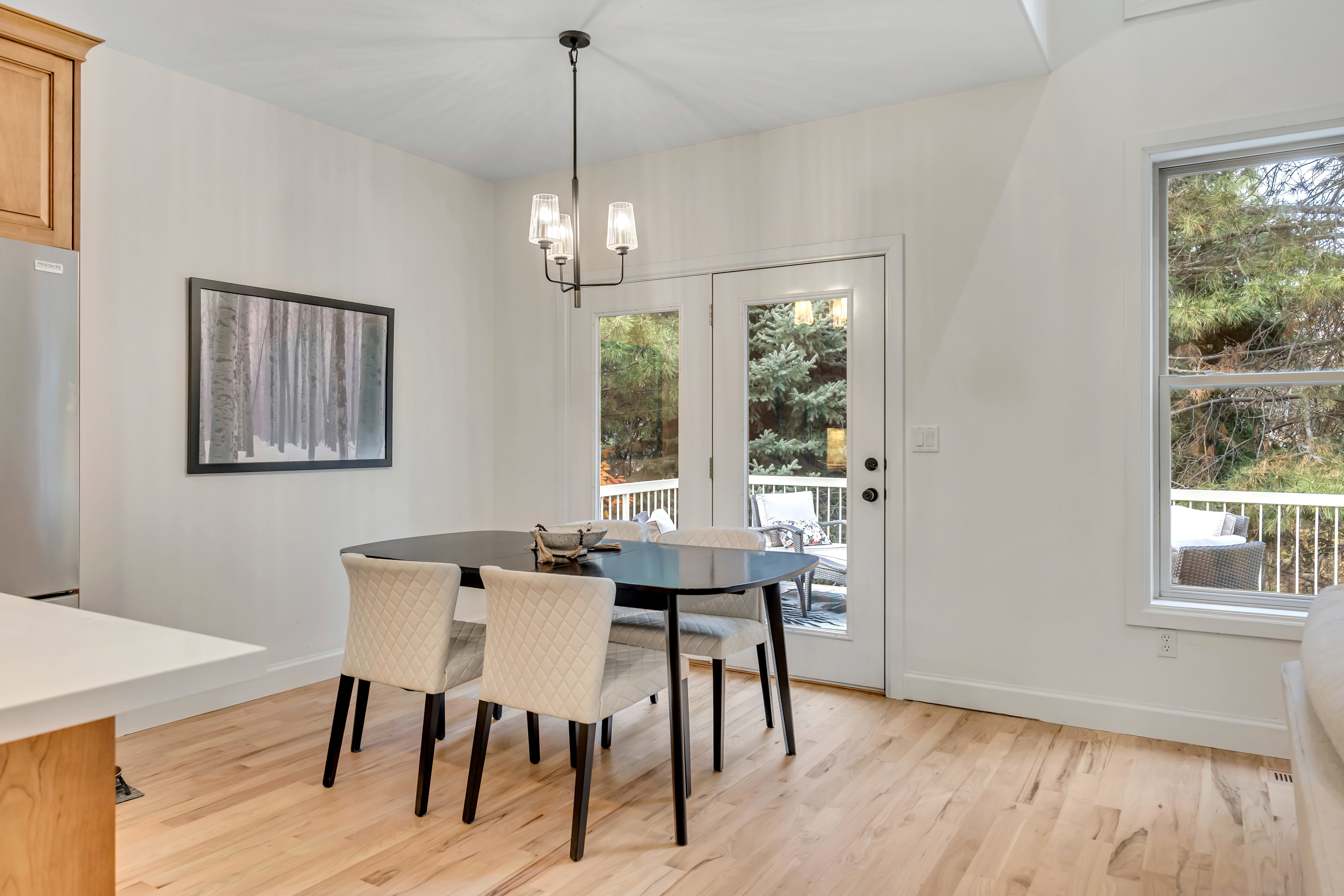 Dining area featuring light wood-finish flooring, white walls, and a contemporary chandelier