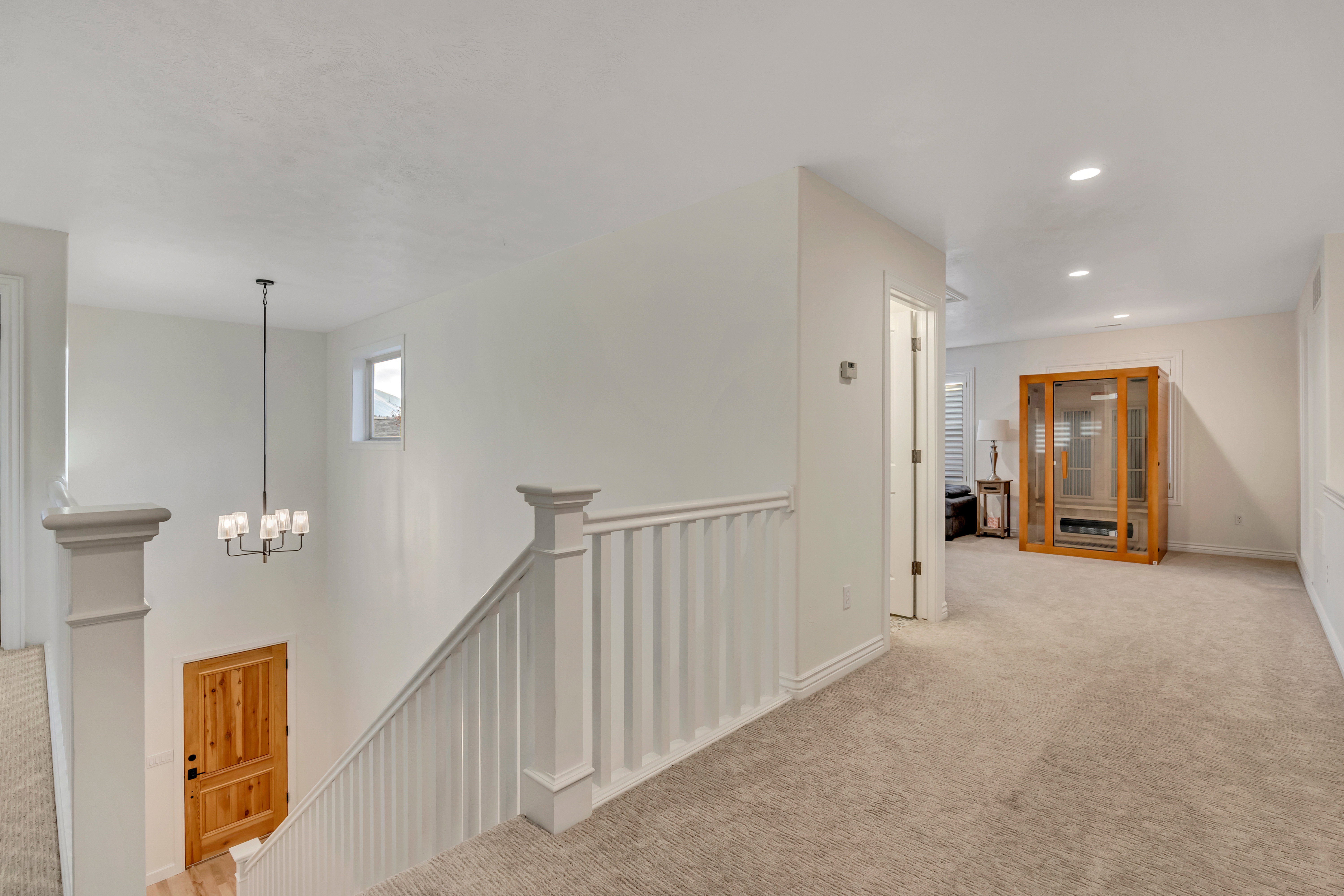Upper landing with neutral carpet, white balustrade, and recessed lighting