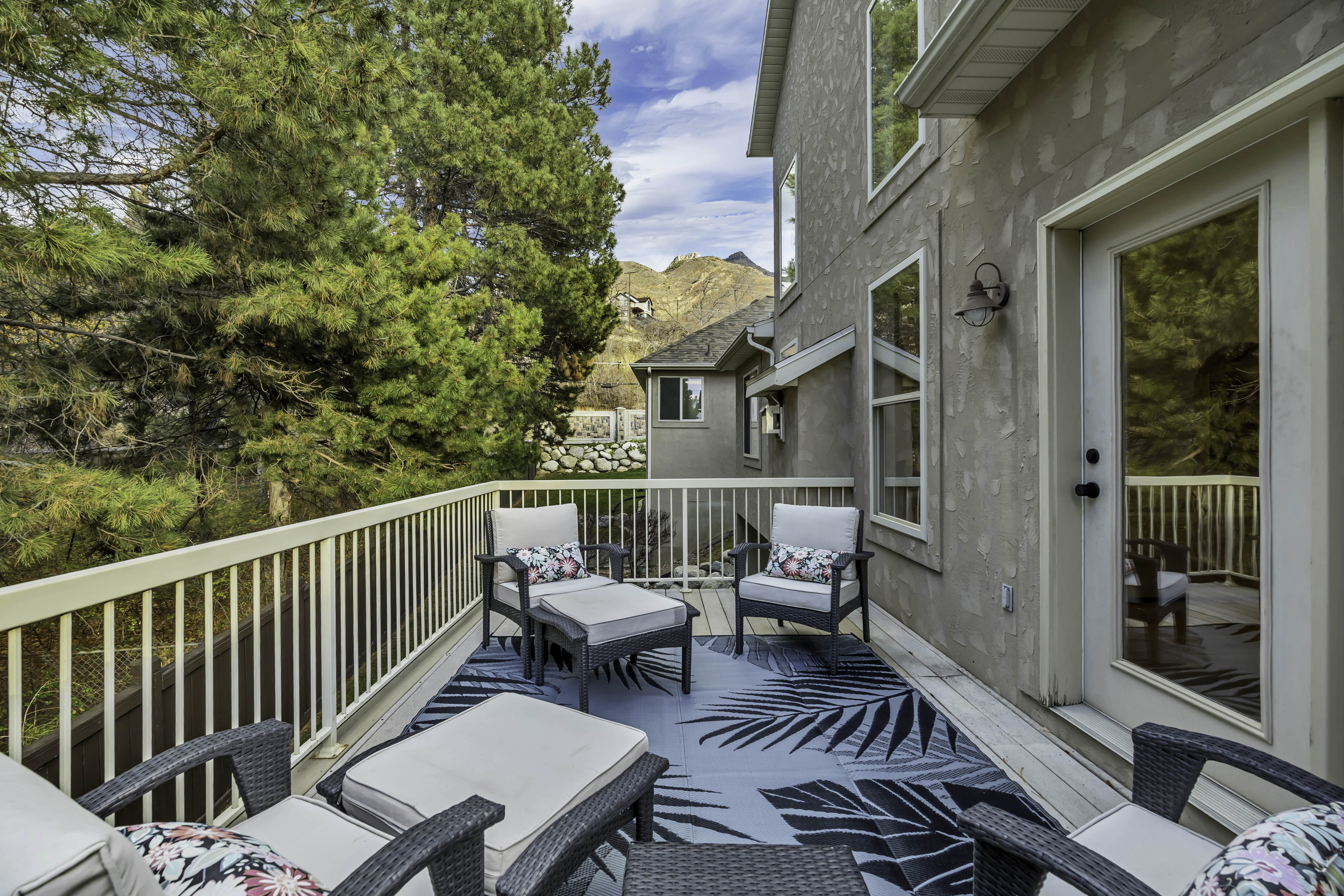 Spacious outdoor deck featuring a decorative area rug, white railing, and a door with frosted glass