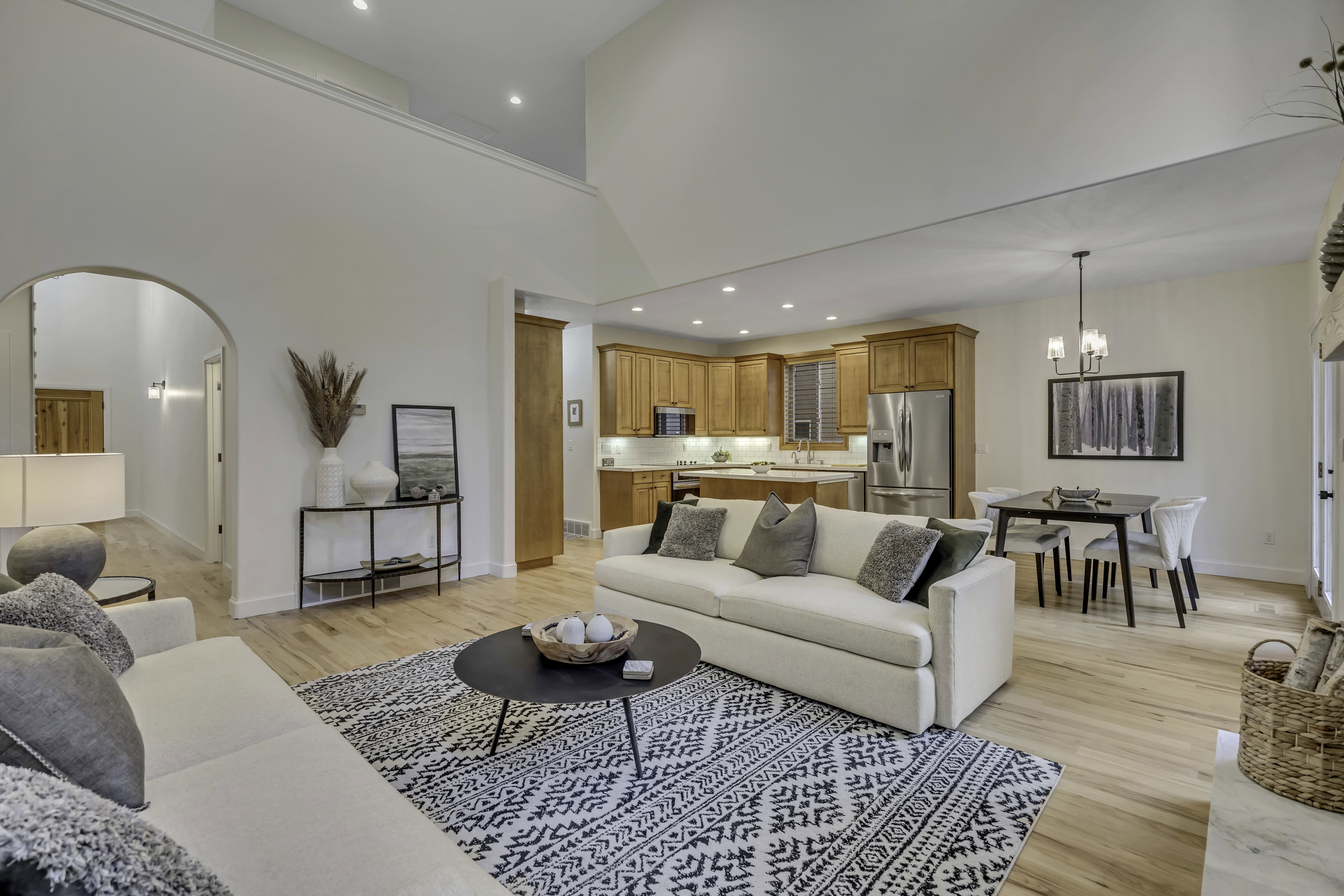 Open-concept living area with light wood-finish flooring, a vaulted ceiling, recessed lighting, and an upper-level overlook