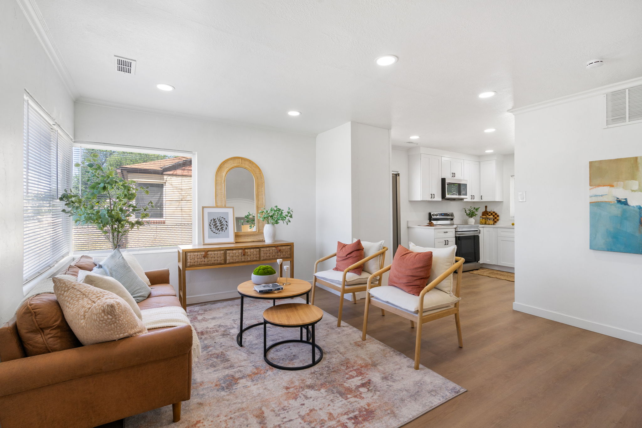 Open-concept living area featuring wood-finish flooring, recessed lighting, and ample natural light from horizontal blinds