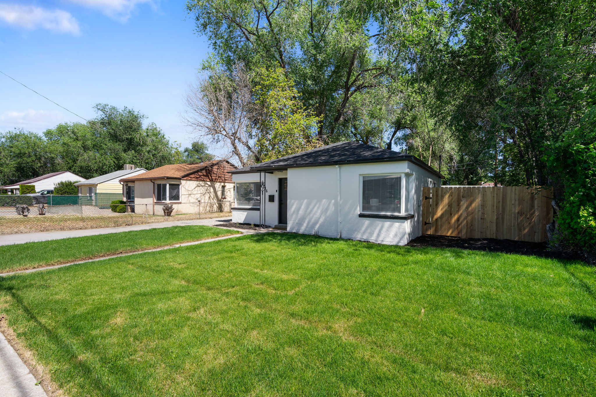 White exterior with black trim, a flat roof, and a wooden privacy fence