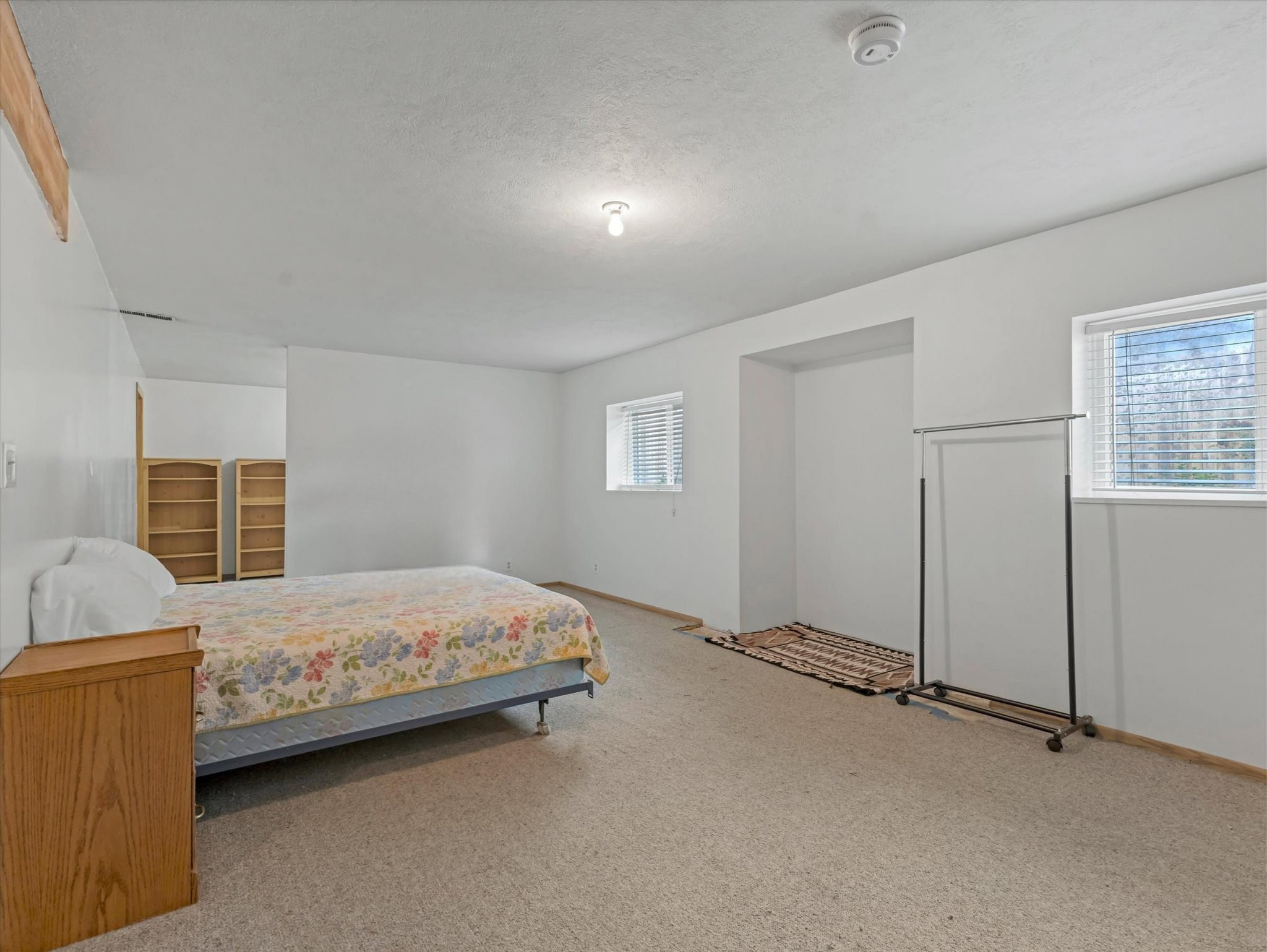 Carpeted room with white walls, two windows featuring blinds, and a built-in recessed area