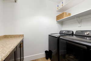Dedicated laundry area featuring a countertop, dark wood-finish cabinetry with brass hardware, and built-in shelving