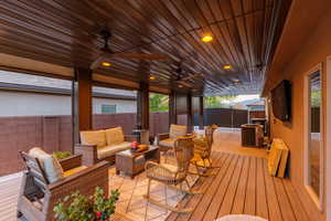 Spacious covered patio featuring a wood-finish slatted ceiling with recessed lighting, integrated ceiling fans, and composite decking