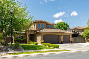 Contemporary stucco exterior featuring a stone accent entry, arched double garage doors, a concrete driveway, and established landscaping