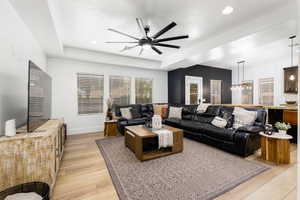 Spacious living area featuring light wood-finish flooring, recessed ceiling lighting, and a modern ceiling fan
