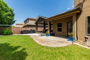 Expansive backyard featuring a manicured lawn and a curved concrete patio with a covered outdoor area