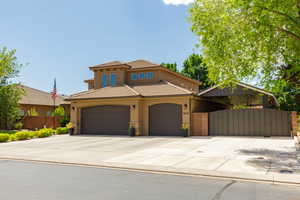 Stucco exterior with a tile roof, featuring a two-car garage with arched doors, and a covered carport