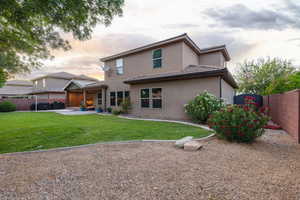 Spacious backyard featuring a manicured lawn, an extended covered patio, and a gravel perimeter